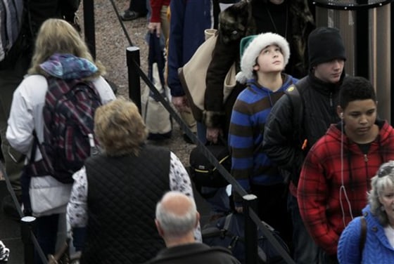 While wearing a green Santa hat, Colter Schoer, 10, of Denver, joins the holiday crowd in the long but swiftly moving security line at Denver International Airport, on Tuesday.